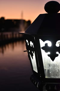 Close-up of silhouette statue by lake against sky during sunset