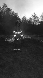 Woman standing on field against trees at night