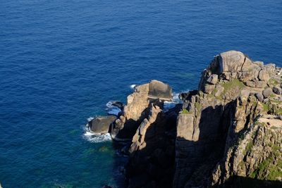 High angle view of rocks by sea against blue sky