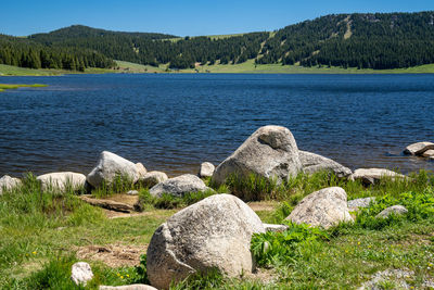 Scenic view of rocks by lake against sky