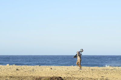 Cameraman walking on ocean beach early morning carrying his video camera baja california sur, mexico