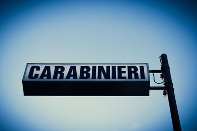 Low angle view of road sign against blue sky