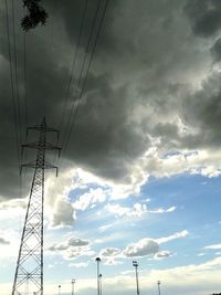 Low angle view of electricity pylon against cloudy sky