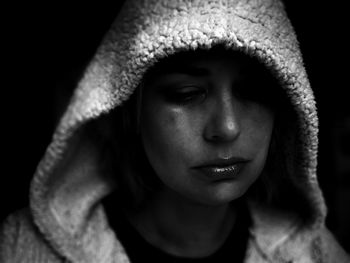 Close-up portrait of woman in hood over black background