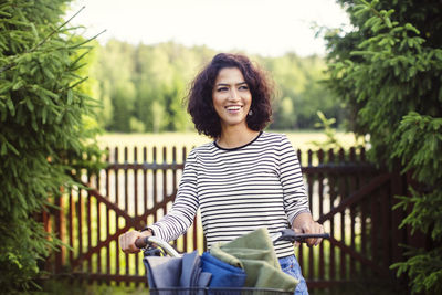 Portrait of smiling young woman against trees