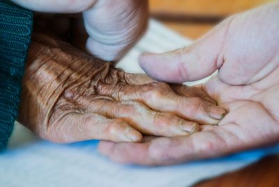 Cropped image of person holding parent hand at table