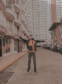 Full length portrait of young man standing against building in city