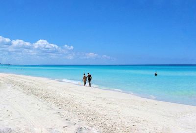 People on beach against blue sky