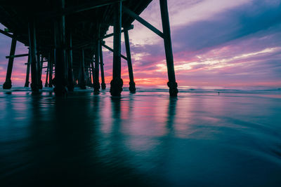 Silhouette pier over sea against sky during sunset