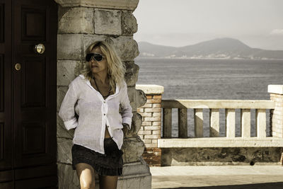 Woman standing by railing against water