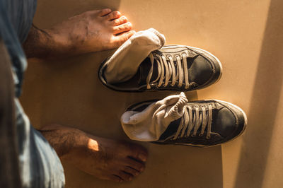 Low section of man standing by shoes on floor