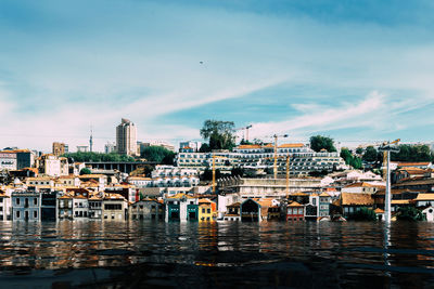 Buildings by river against sky in city