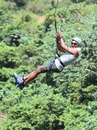 Full length of man hanging on zip line in forest