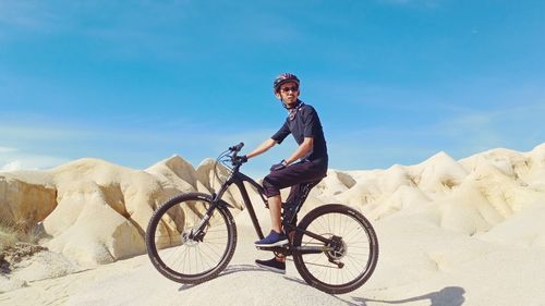 Man riding bicycle on mountain against sky