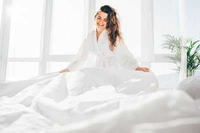 Woman making bed in the sunny morning. woman doing morning routine.