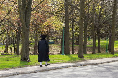 Orthodox hasidic jew man wearing the traditional fur hat and black coat walking along a park