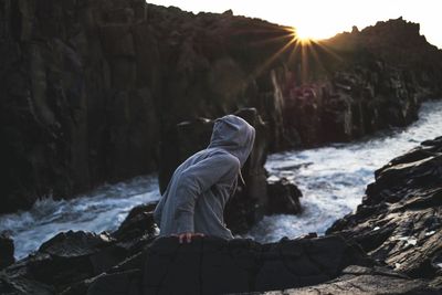 Rear view of person standing on rocks against river