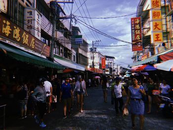 People walking on street amidst buildings in city