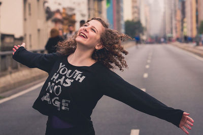 Young woman smiling while standing on road in city