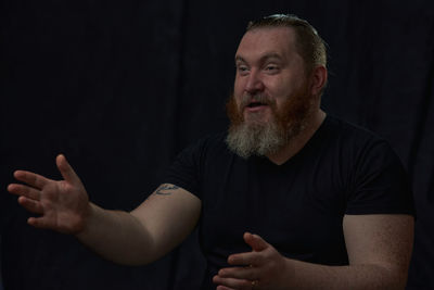 Portrait of senior man looking away against black background