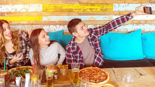 Man with happy friends taking selfie at restaurant