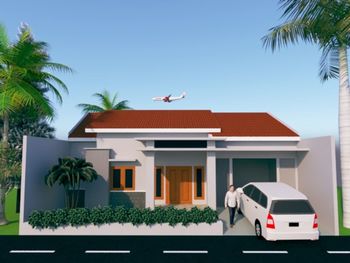 House and palm trees by building against clear sky