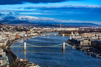 View of city at waterfront against cloudy sky