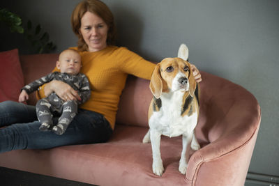 Happy grandmother,baby grandson and cute beagle dog on sofa at home