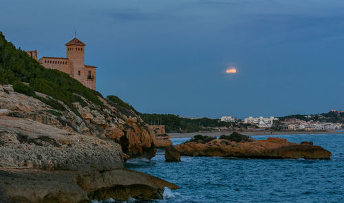 Scenic view of sea by buildings against sky