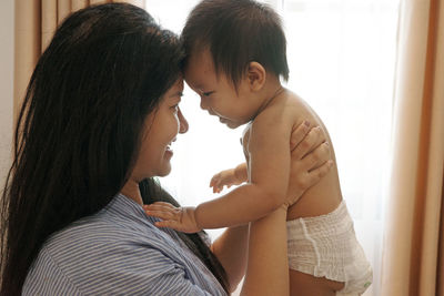 A happy asian mother is gently touching her baby