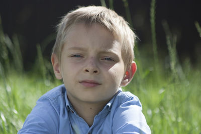 Close-up portrait of boy sitting on field