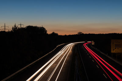 Light trails on road against sky at night