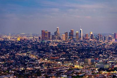 Aerial view of buildings in city against cloudy sky