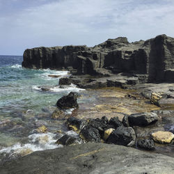 Rocks on sea shore against sky