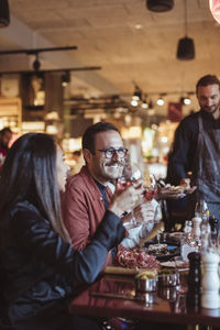 Smiling male and female friends having alcohol in bar