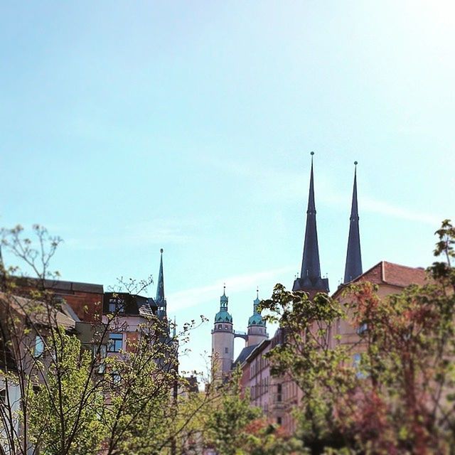 architecture, building exterior, built structure, clear sky, place of worship, low angle view, church, religion, tree, copy space, spirituality, tower, city, sky, spire, steeple, residential building, residential structure