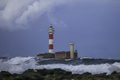 Lighthouse by sea against sky