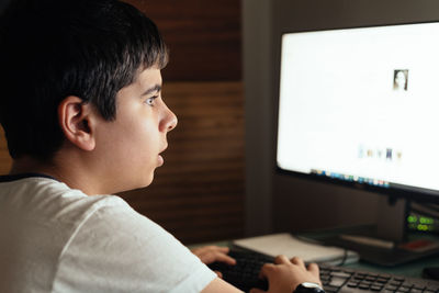 Side view of boy looking through mobile phone on table