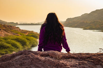 Isolated young girl at mountain top with lake view backbit shot from flat angle