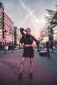 Full length portrait of young woman standing in city