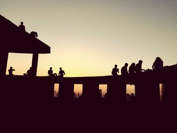 Silhouette people against clear sky at sunset