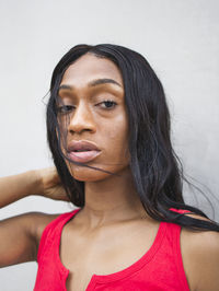 Confident african american female with black hair looking at camera while standing on white background on street