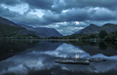 Scenic view of lake and mountains against cloudy sky