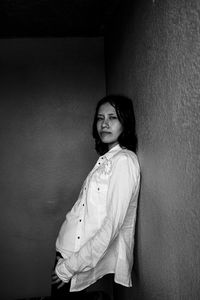 Portrait of young woman standing against wall