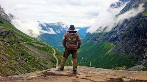 Rear view of man standing on mountain road against mountains