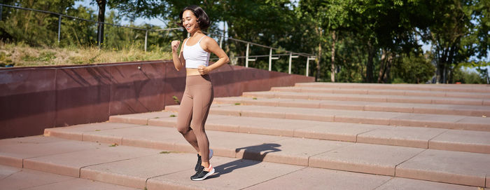 Full length of young woman standing on footpath