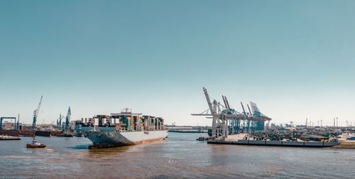 Cranes at harbor against sky