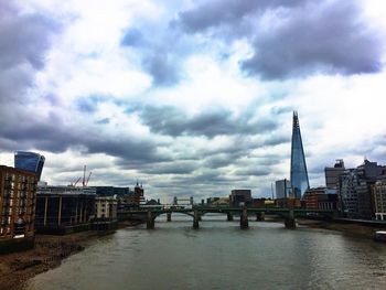 Bridge over river against cloudy sky