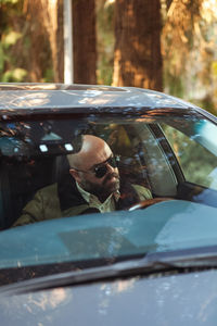 Brutal bald bearded middle-aged man drives a car