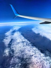 Airplane flying over sea against blue sky